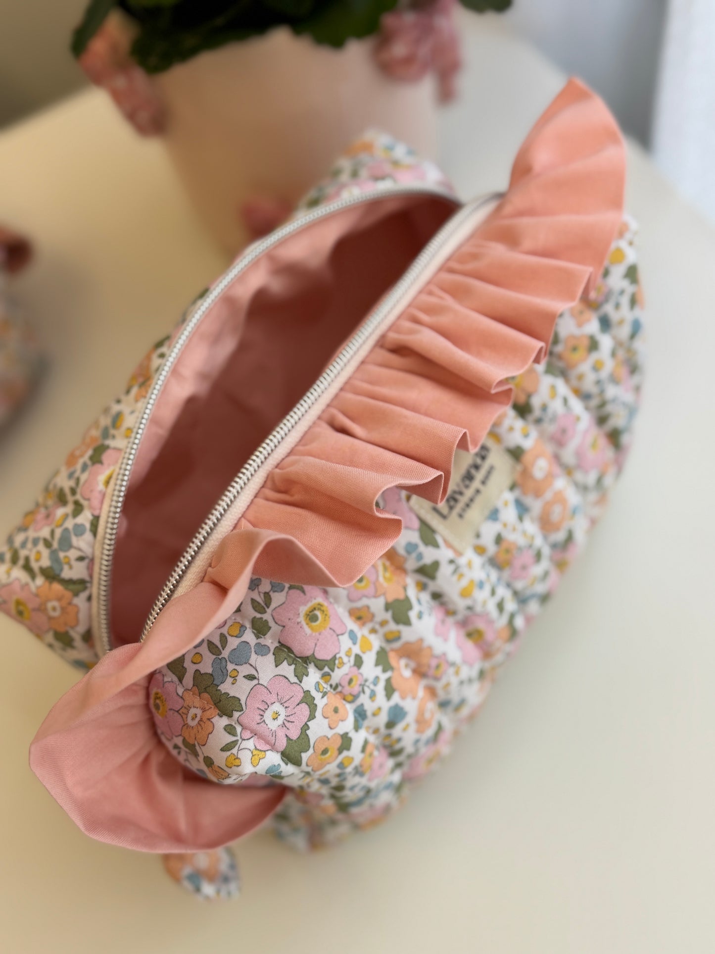 Bolsa de cosméticos Fresia com estampado de flores e folhos.